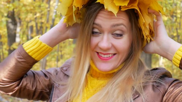Smiling happy woman portrait with yellow leaf wreath in autumn park