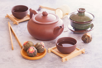 Green tea in buds, brown ceramic teapot with a cup prepared for a traditional Asian tea ceremony stand on a gray table