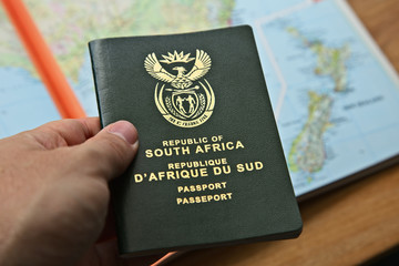 A South African travel passport in a man's hand with map in the background. This image can be used...