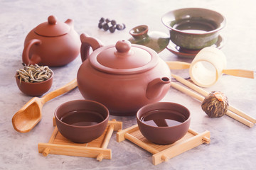 Traditional Chinese tea cups, ceramic teapot and tea ceremony attributes are on a gray table.