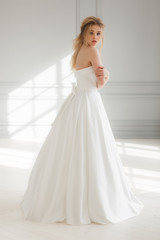 Fototapeta premium Young bride in luxury wedding dress looking back through shoulder. catalog of wedding dresses
