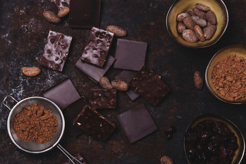 Chopped chocolate, cocoa beans, cocoa powder on rusty metal background. Toned. Haze effect