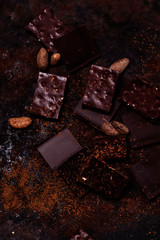 Chopped chocolate, cocoa beans, cocoa powder on rusty metal background