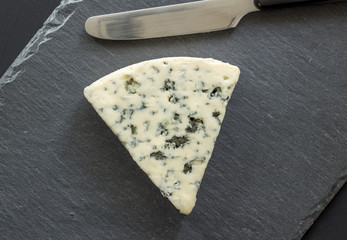 Roquefort cheese wedge top view photo on black slate