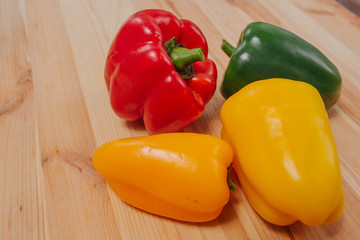 Close-up view of red, green, yellow and orange paprika and group, tasty vegetable in a wood background in the kitchen.