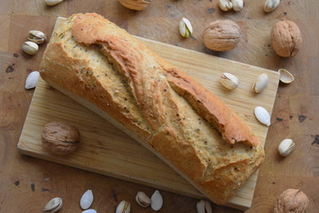 Pan sobre una tabla de madera, nueces y pistachos encima de la mesa 