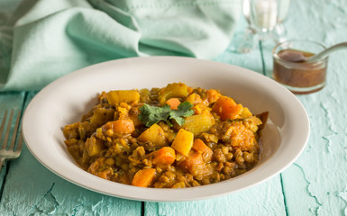 Lentil and vegetable curry on rustic blue wooden table close up with chutney in the background