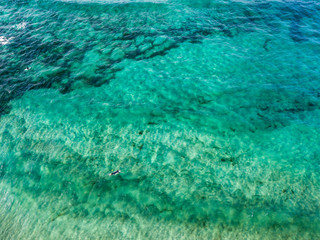 Vista aerea di un mare cristallino con onde e surfisti. Onde che si infrangono sulla spiaggia al tramonto, controluce. Playa De La Canteria. Oceano Atlantico. Orzola, Lanzarote, Isole Canarie. Spagna