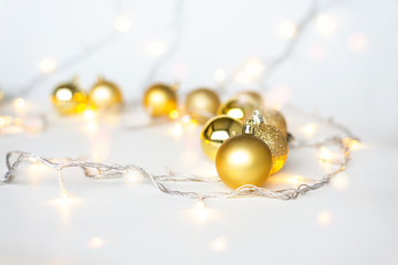 Christmas lights in warm yellow white on string and gold xmas balls over light background with copy space for text, logo decoration on Xmas eve celebration, special holidays, new year event concept
