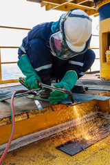 Industrial welder worker holding welding torch during perform welding sheet metal steel plate in construction factory by wearing heat protection gloves with smoke, spark, arc, fire, flash, hot