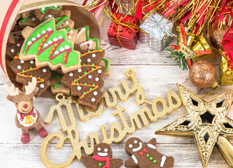 Beautiful Christmas composition and decoration with baked Christmas gingerbread cookie in paper bag on light wooden background, flat lay, top view, copy space (text space)