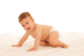 Hapy baby boy in playing on bed isolated over white