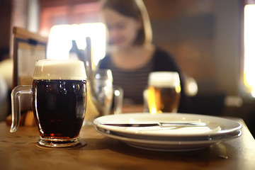 mug of dark beer in the interior of  pub / pint of beer with foam on a served table in  beer restaurant in Czech Republic