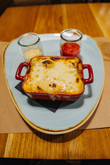 Italian classic dish lasagna with vegetables and cheese on a wooden background.