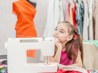 Dreaming little girl at the sewing machine. Choice of profession concept