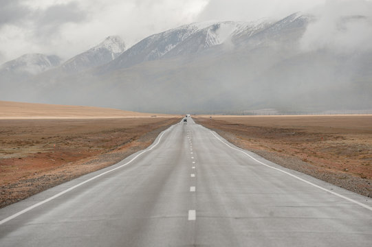A long straight road leading towards a mountain. Russia, Altai, Kurai steppe