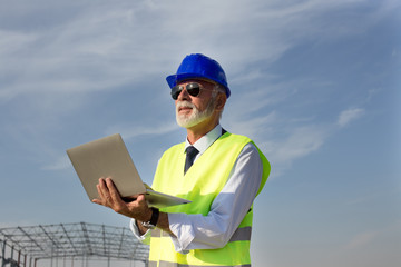 Engineer with laptop at building site