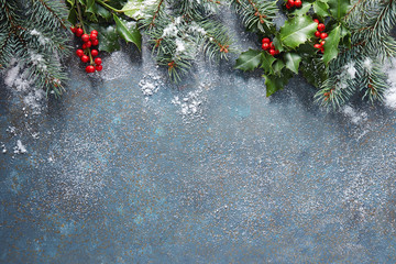 Christmas background with fir tree and holly berry, covered in snow, with copy space.