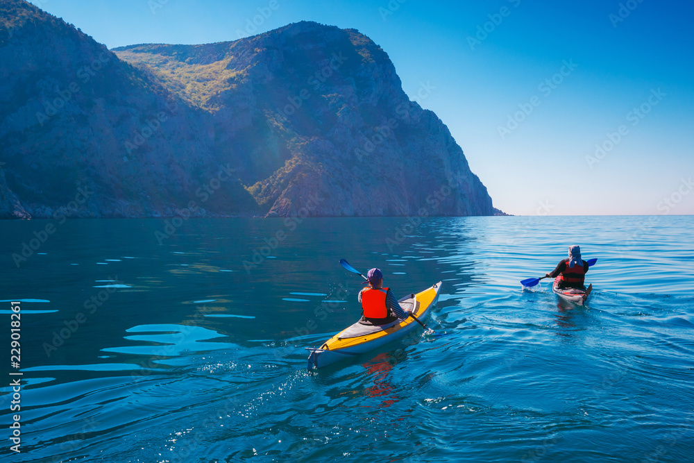 Wall mural kayaking. people swim in the sea kayak near the mountains. adventures on the water