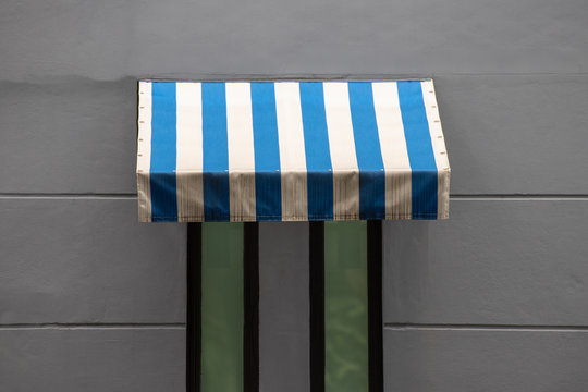 blue and white striped awning over small window.