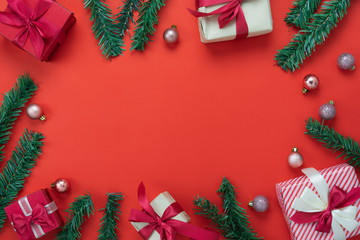 Table top view of Merry Christmas decorations & Happy new year ornaments concept.Flat lay essential difference objects gift box & fir tree on modern red paper background at home studio office desk.