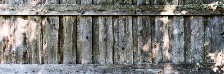 Wooden fence with nails, moss and sun glare