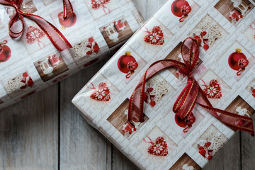 Christmas presents wrapped in red and white paper, decorated with ribbons, on a light, rustic wooden background