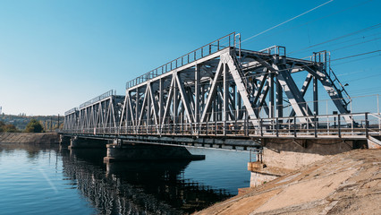 Steel railway bridge over river, perspective. Train transportation