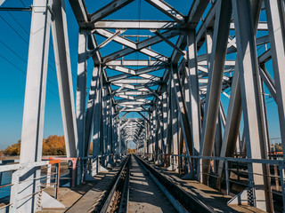 Steel railway bridge over river, perspective. Train transportation