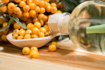 Sea-buckthorn oil and berries buckthorn branch in bowl on a wooden background. selective focus image 
