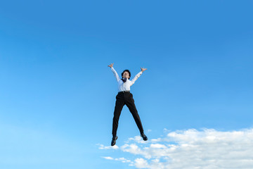 Fototapeta na wymiar 青空をバックにバンザイしながらジャンプするYシャツ姿の若いビジネスマン1人。成功・達成・成就・元気・健康イメージ