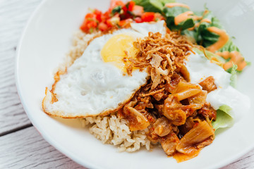 Fusion food Rice bowl toppings kimchi pork, organic fried egg, Korean eggplant and salad.