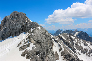On peak of Dachstein and view alpine mountains. National park in Austria, Europe. Blue and cloudy sky in summer day