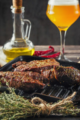 grilled meat steaks on frying pan and glass of beer on a dark wooden background