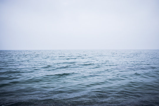 Clean and calm blue sea or ocean. Mist above the water surface. Image with place for your text.