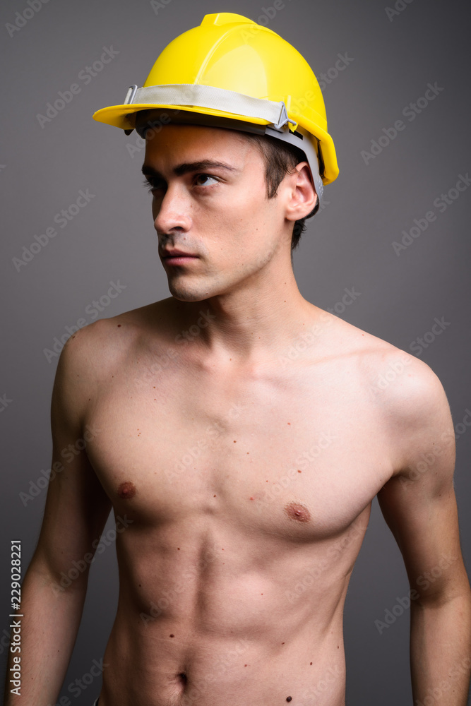 Wall mural handsome sexy man construction worker shirtless against gray ba