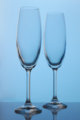 Two long champagne glasses. Blue lighting.