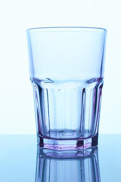 Empty drinking glass cup. Blue lighting. White background.