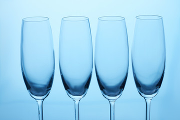 Four empty glasses for champagne and wine. Close up. Blue lighting.