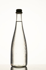 Filled glass bottle with clear water. Dew on the bottle surface. Isolated on white.