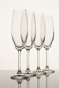 Four fragile goblets for wine or champagne. White background. Reflective surface.