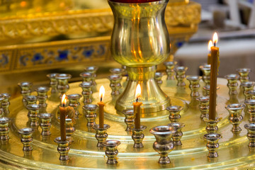 Church candlestick of gold color is partially filled with candles
