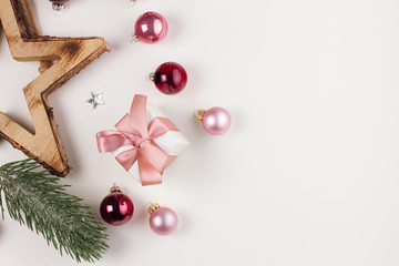 Christmas flat lay scene with pink glass balls and gift box, copy space on white desk