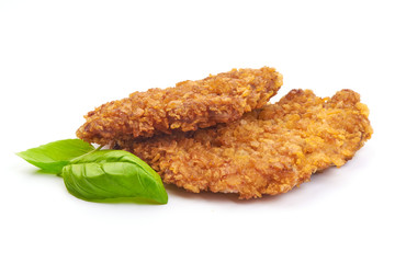 Fried breaded chicken fillet with basil leaves, isolated on a white background. Close-up.