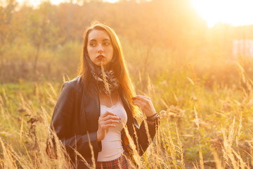 beautiful sad young woman walking at dry grass, sunset time