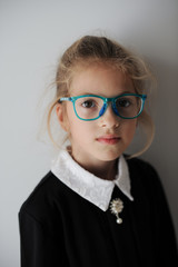 art portrait of pretty little girl in retro school uniform wearing blue glasses