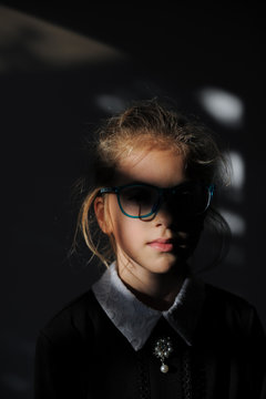 mysterious dark portrait mind concept of small girl in school dress and glasses