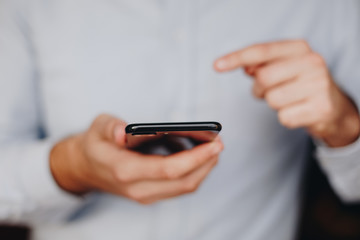 close up of man using smartphone. concept of phone addiction. young business man typing and browsing social media on his phone. 
