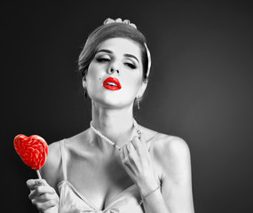 Woman eating lollipops. Girl in pin-up style hold striped candy. Pin up retro female style. Black...