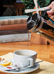 pouring herbal tea with french press teapot into white cup